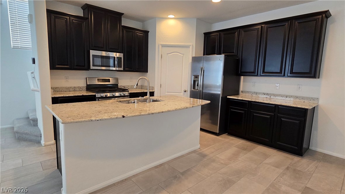 891 Earth Luster Road Las Vegas, NV 89178 - Photo 5 of 20 Granite countertops and dark cabinetry create a sophisticated workspace in this open kitchen.