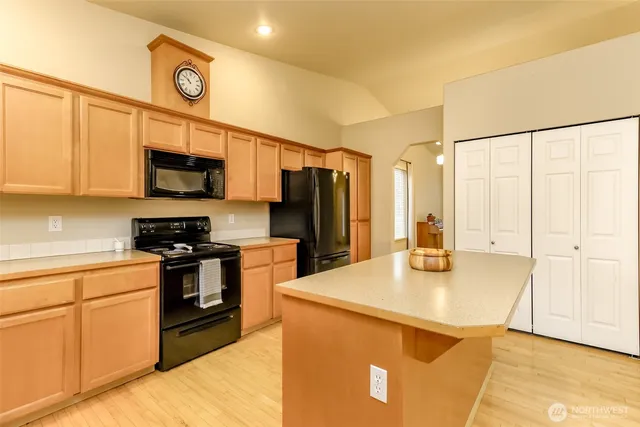 a kitchen with stainless steel appliances granite countertop a refrigerator a stove a sink a microwave and island