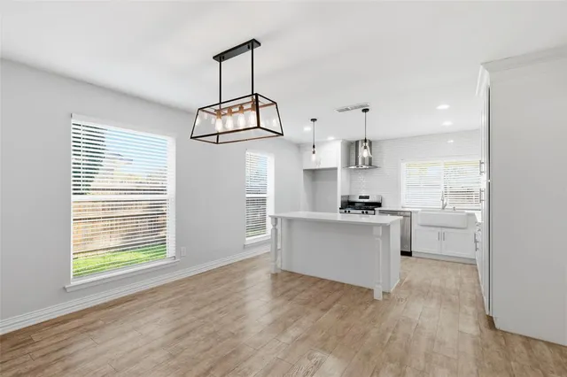 a kitchen with stainless steel appliances granite countertop a stove a sink and white cabinets with wooden floor