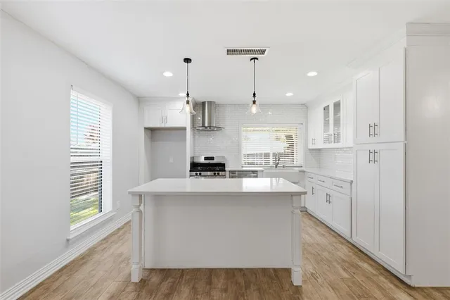 a kitchen with white cabinets appliances a sink and a window