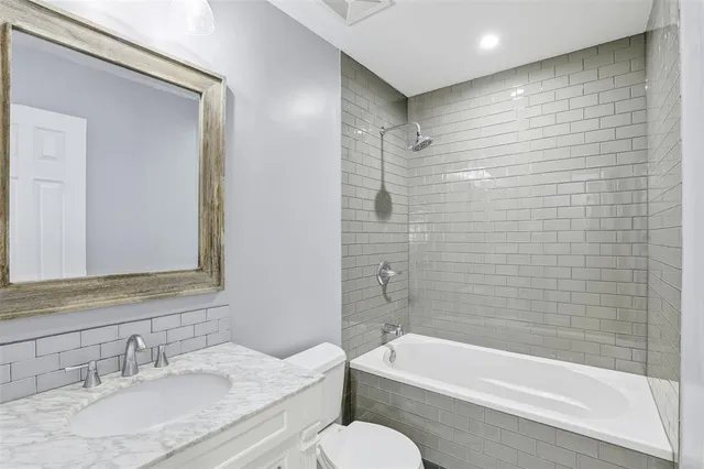 a bathroom with a granite countertop sink toilet and bathtub