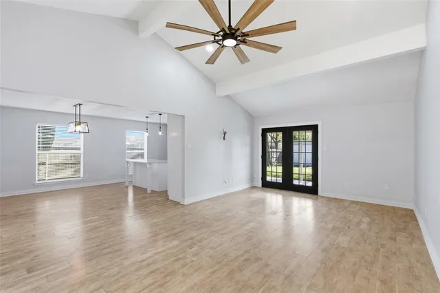 a view of an empty room with window and wooden floor