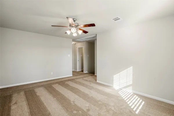 a view of an empty room with chandelier fan