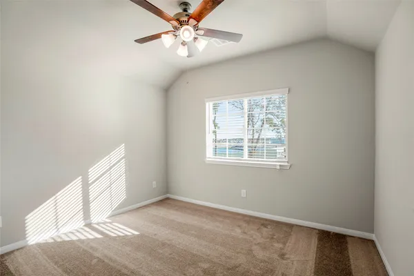 an empty room with chandelier fan and windows