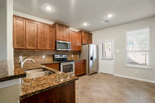 a kitchen with stainless steel appliances granite countertop a stove top oven a sink dishwasher a refrigerator and cabinets with wooden floor