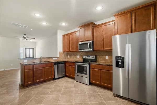 a kitchen with stainless steel appliances granite countertop a refrigerator sink and stove