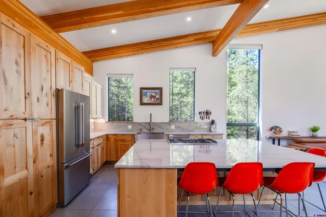 a kitchen with stainless steel appliances kitchen island granite countertop a table chairs and a refrigerator