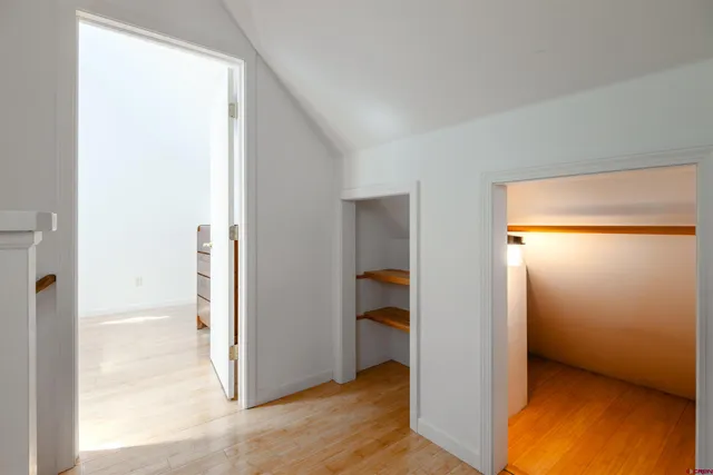 a view of an empty room with wooden floor and a bedroom