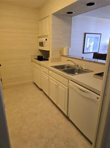 a view of a refrigerator in kitchen and an empty room