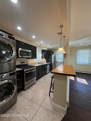 a kitchen with stainless steel appliances kitchen island granite countertop a sink a stove top oven a counter space and cabinets