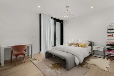a bedroom with a bed a chair and potted plant on a dresser