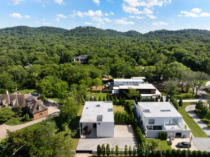 an aerial view of residential houses with outdoor space and trees