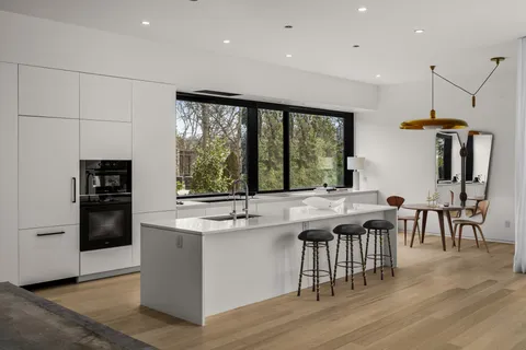 a kitchen with stainless steel appliances granite countertop a stove a refrigerator a kitchen island a dining table and chairs with wooden floor