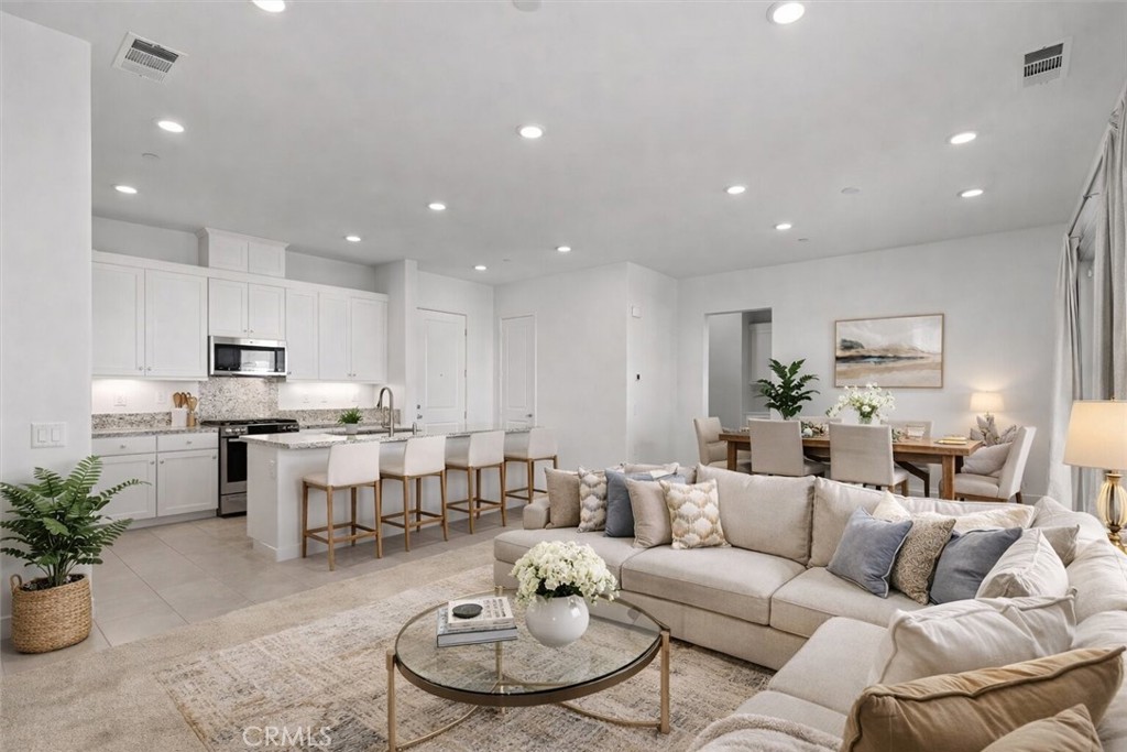 a living room with furniture kitchen and a potted plant
