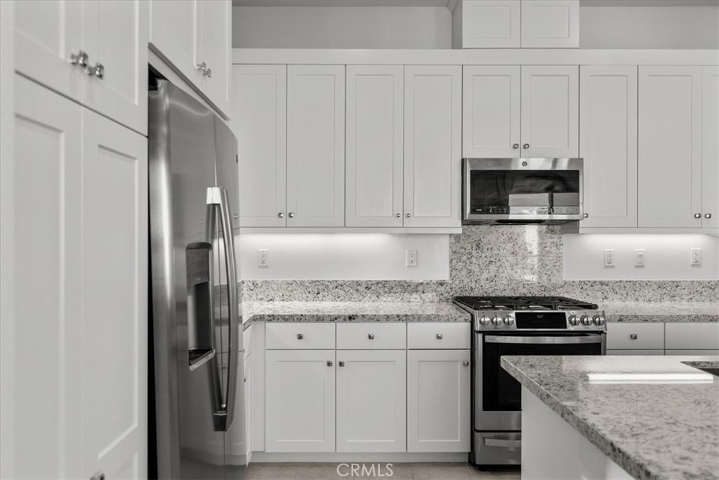 27410 Merlin Place, Unit 305 Valencia, CA 91381 - Photo 18 of 32 a kitchen with granite countertop white cabinets and stainless steel appliances