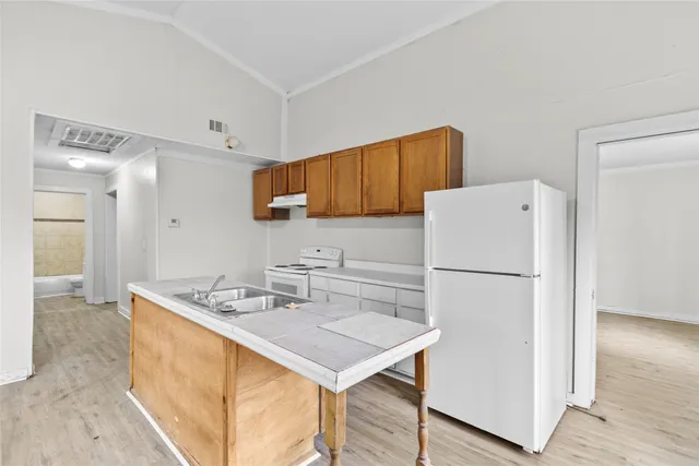 a white kitchen with a sink a refrigerator and a stove