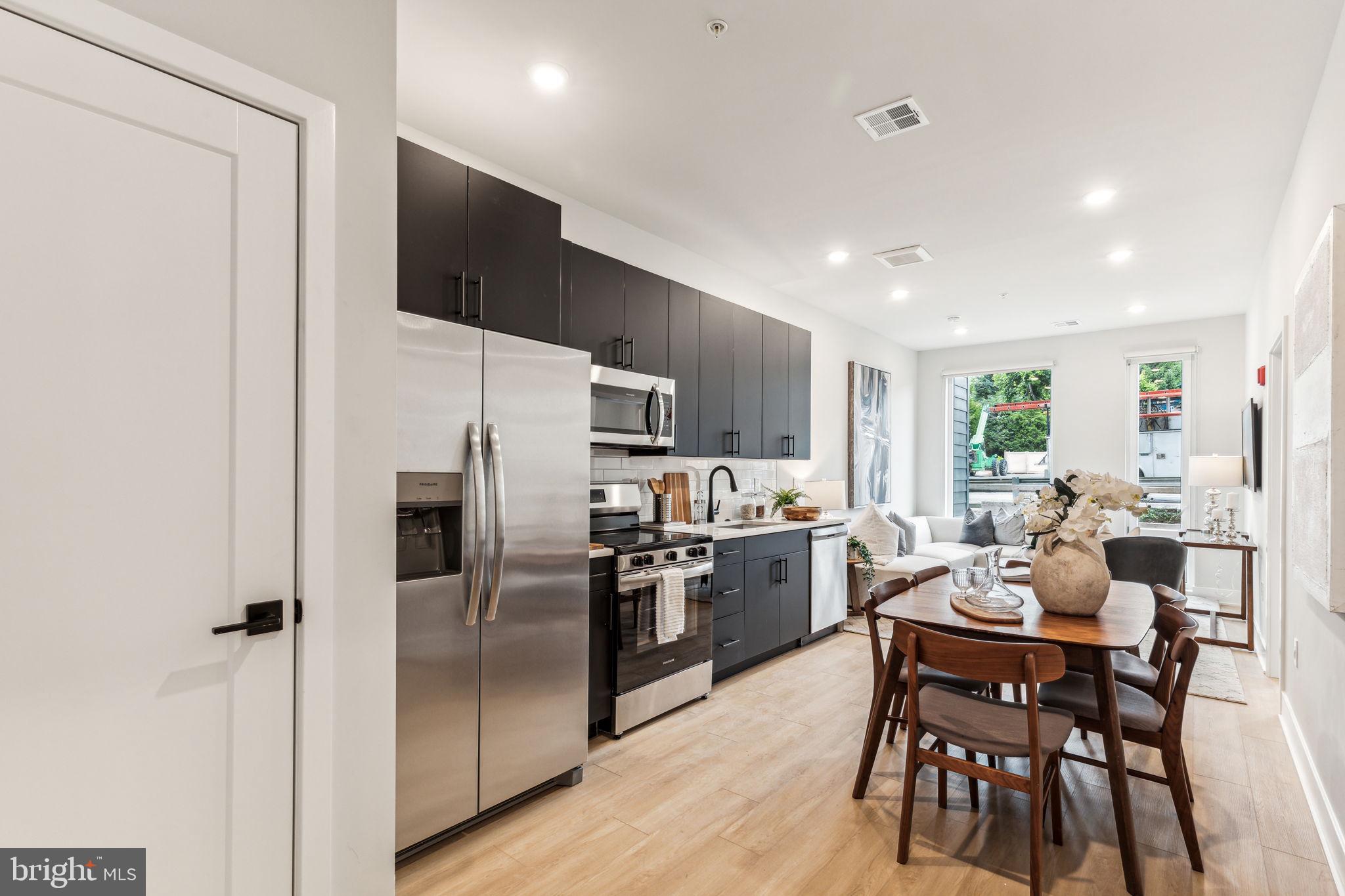 6910 Ridge Avenue, Unit 110 Philadelphia, PA 19128 - Photo 3 of 19 a kitchen with a table chairs refrigerator and microwave