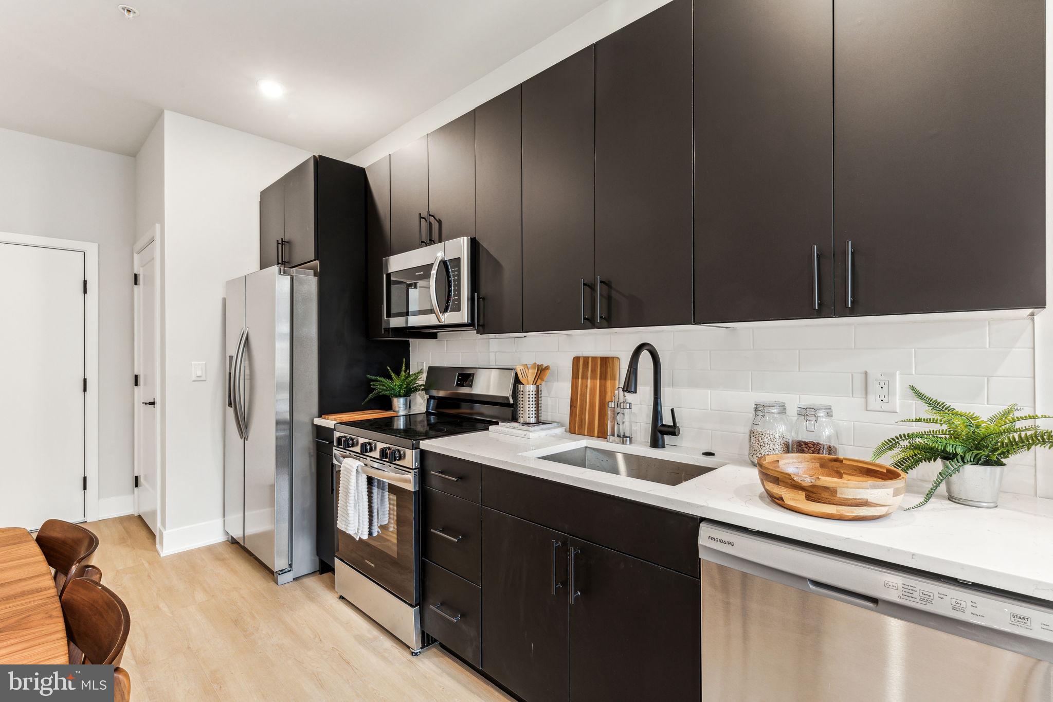 6910 Ridge Avenue, Unit 110 Philadelphia, PA 19128 - Photo 9 of 19 a kitchen with stainless steel appliances a sink a stove a refrigerator and cabinets