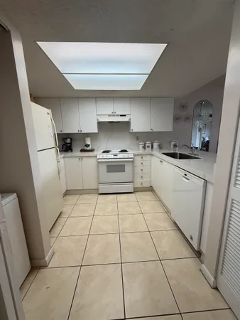 a kitchen with a sink a stove top oven and cabinetry