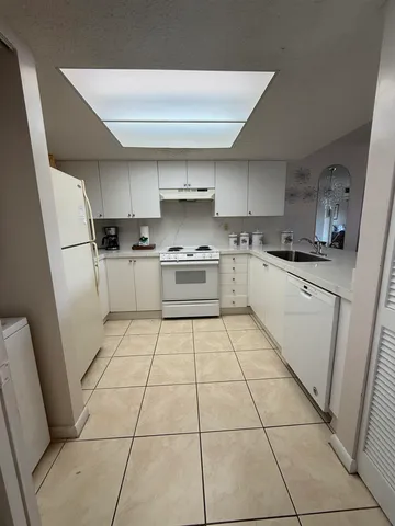 a kitchen with a sink a stove top oven and cabinetry