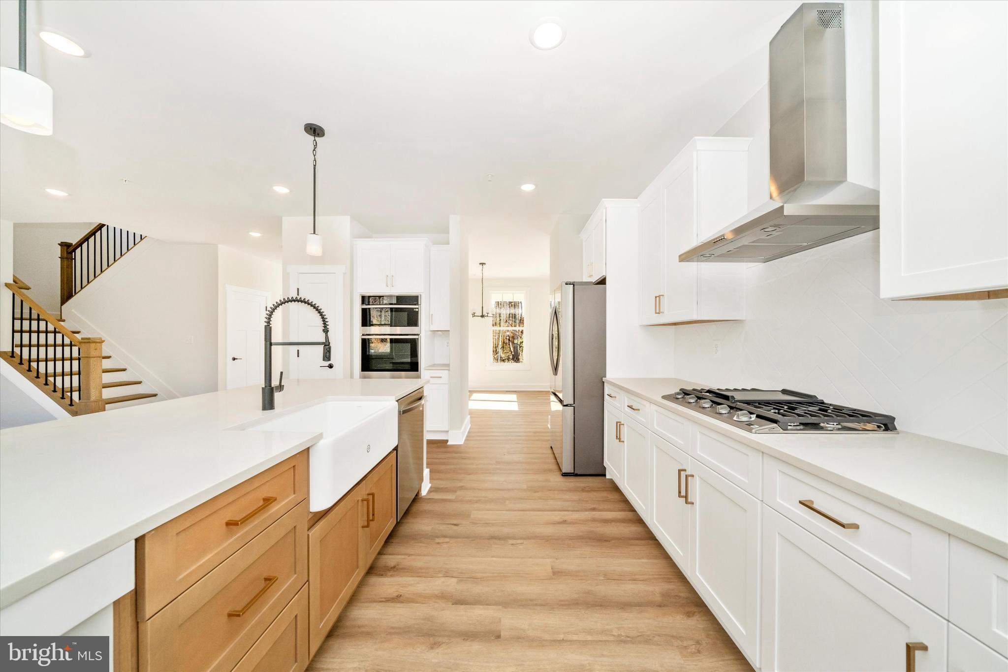 1156 Mt Zion Marlboro Road Lothian, MD 20711 - Photo 21 of 73 a large kitchen with kitchen island a stove a sink a refrigerator and white cabinets with wooden floor