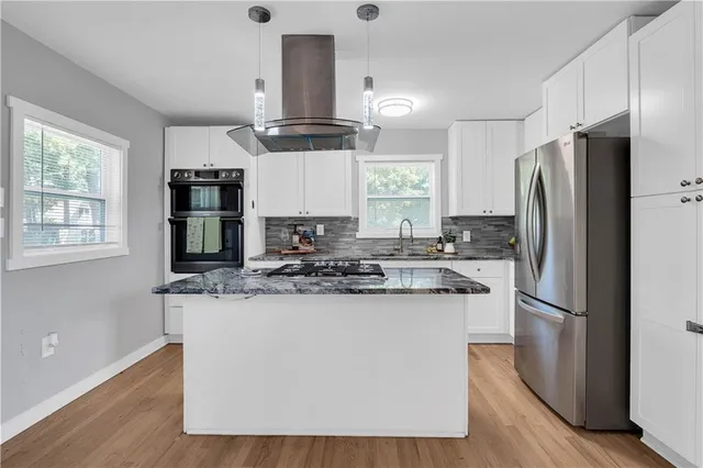 a kitchen with kitchen island stainless steel appliances a sink and a refrigerator
