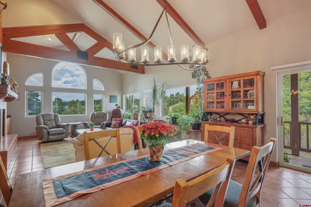 a view of a dining room with furniture a chandelier and large windows