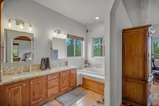 a spacious bathroom with a double vanity sink a mirror and a bathtub