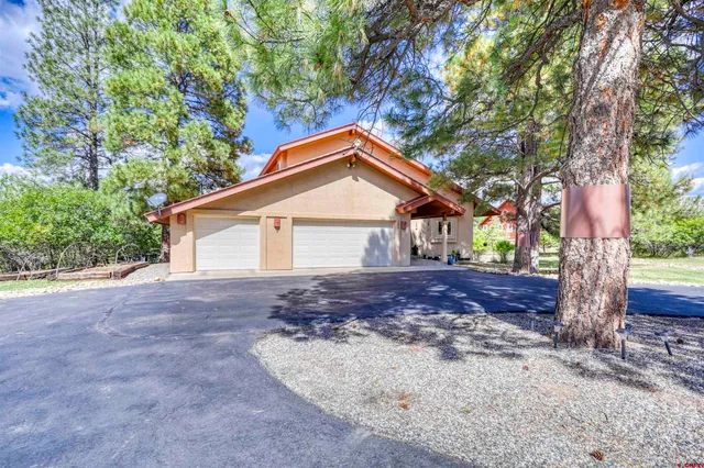 a view of a house with a yard and large tree