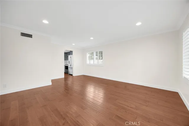 a view of empty room with wooden floor and window