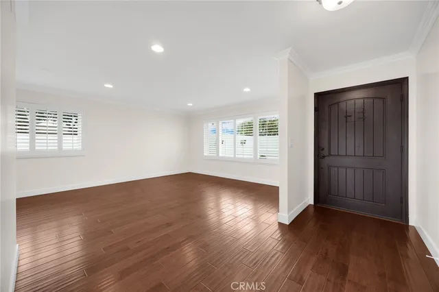 an empty room with wooden floor cabinet and windows