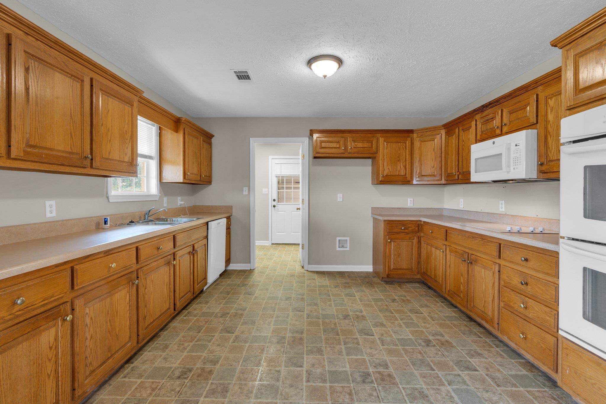 276 Mcbroom Road Henning, TN 38041 - Photo 12 of 36 Kitchen with white appliances, sink, and a textured ceiling