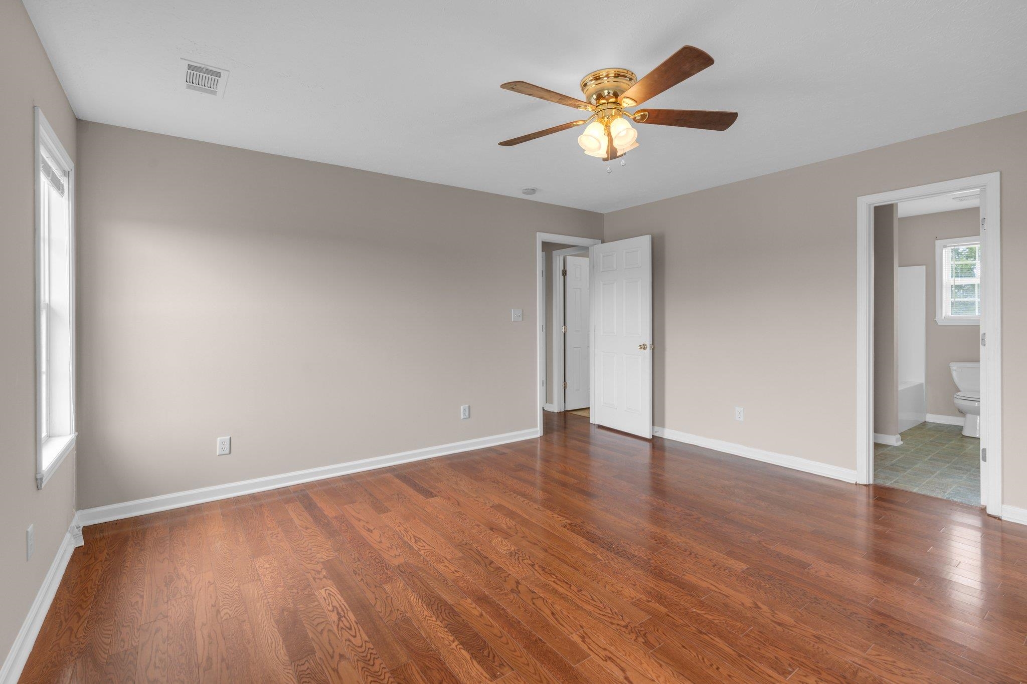 276 Mcbroom Road Henning, TN 38041 - Photo 15 of 36 Unfurnished bedroom featuring ceiling fan, ensuite bathroom, and hardwood / wood-style flooring