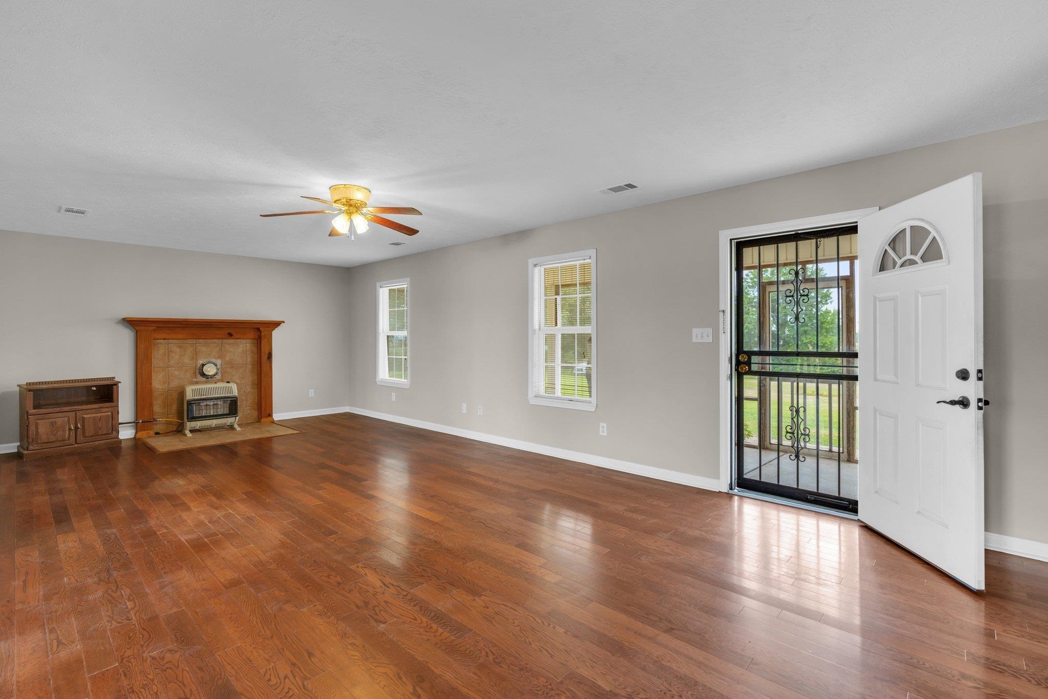 276 Mcbroom Road Henning, TN 38041 - Photo 6 of 36 Unfurnished living room with dark hardwood / wood-style flooring, a wood stove, and ceiling fan