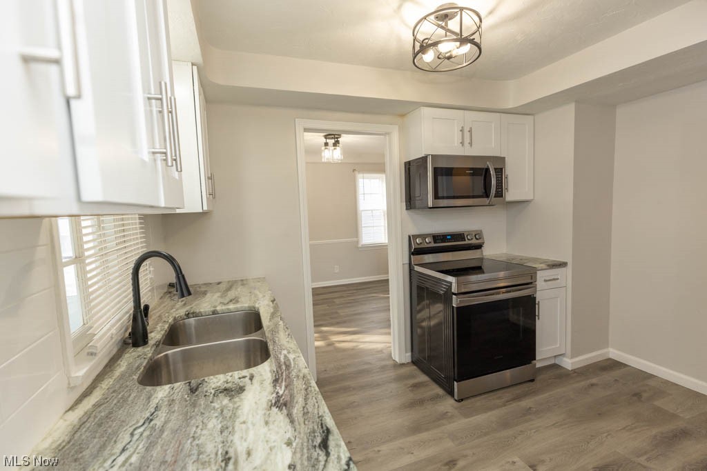 3890 Wallingford Road South Euclid, OH 44121 - Photo 8 of 19 Kitchen featuring light stone countertops, white cabinets, light hardwood / wood-style flooring, stainless steel appliances, and sink