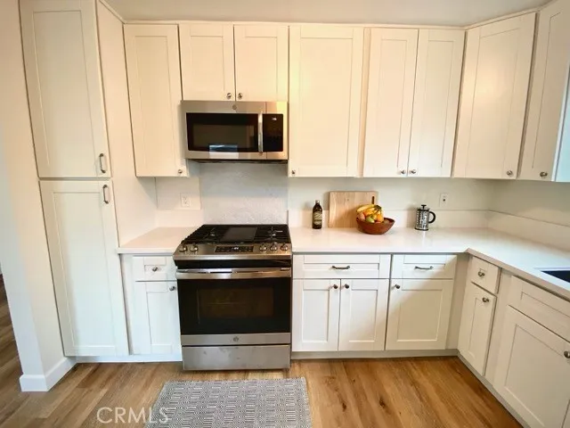 a kitchen with stainless steel appliances granite countertop a stove a microwave and a white cabinets