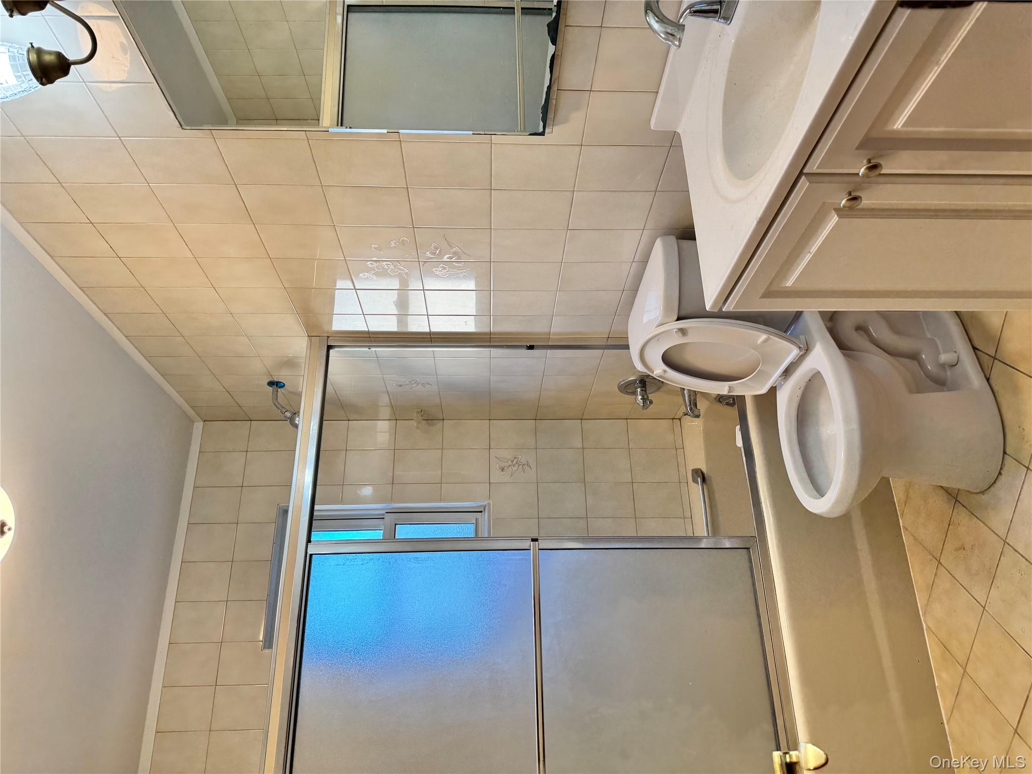 259-07 147th Road Queens, NY 11422 - Photo 12 of 27 Full bath with tile patterned flooring, toilet, vanity, tile walls, and bath / shower combo with glass door