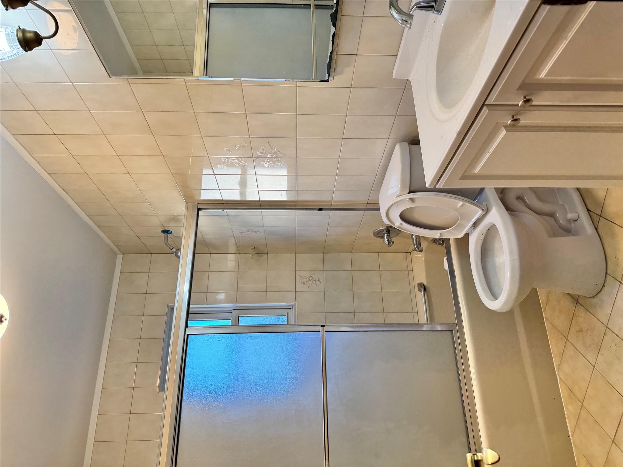 259-07 147th Road Queens, NY 11422 - Photo 13 of 24 Full bath with tile patterned flooring, toilet, vanity, tile walls, and bath / shower combo with glass door