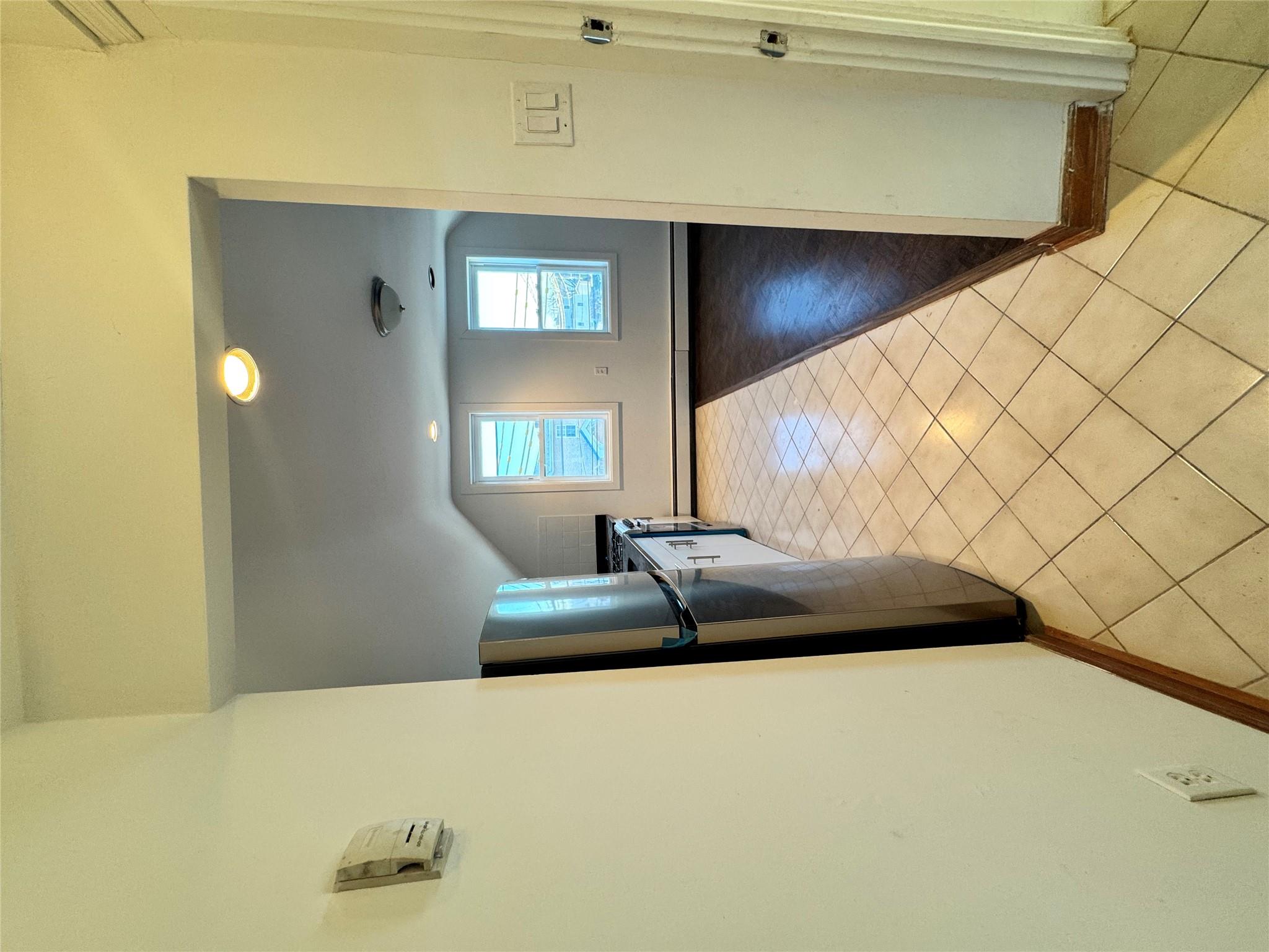 259-07 147th Road Queens, NY 11422 - Photo 14 of 24 Kitchen featuring fridge, a baseboard heating unit, light tile patterned flooring, baseboards, and lofted ceiling