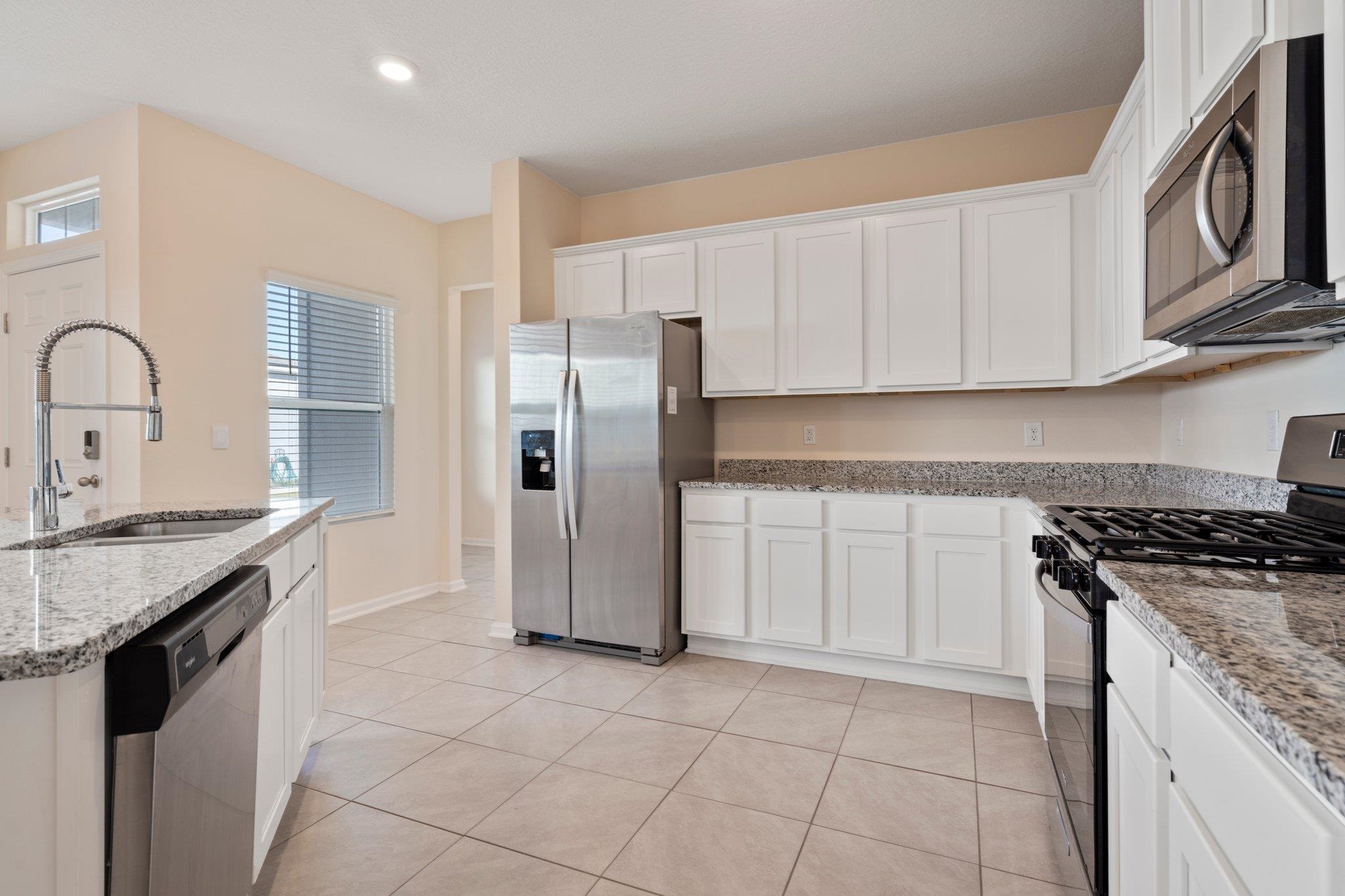 553 Coastline Way Street St. Augustine, FL 32092 - Photo 4 of 35 a kitchen with stainless steel appliances granite countertop a stove a refrigerator and a sink