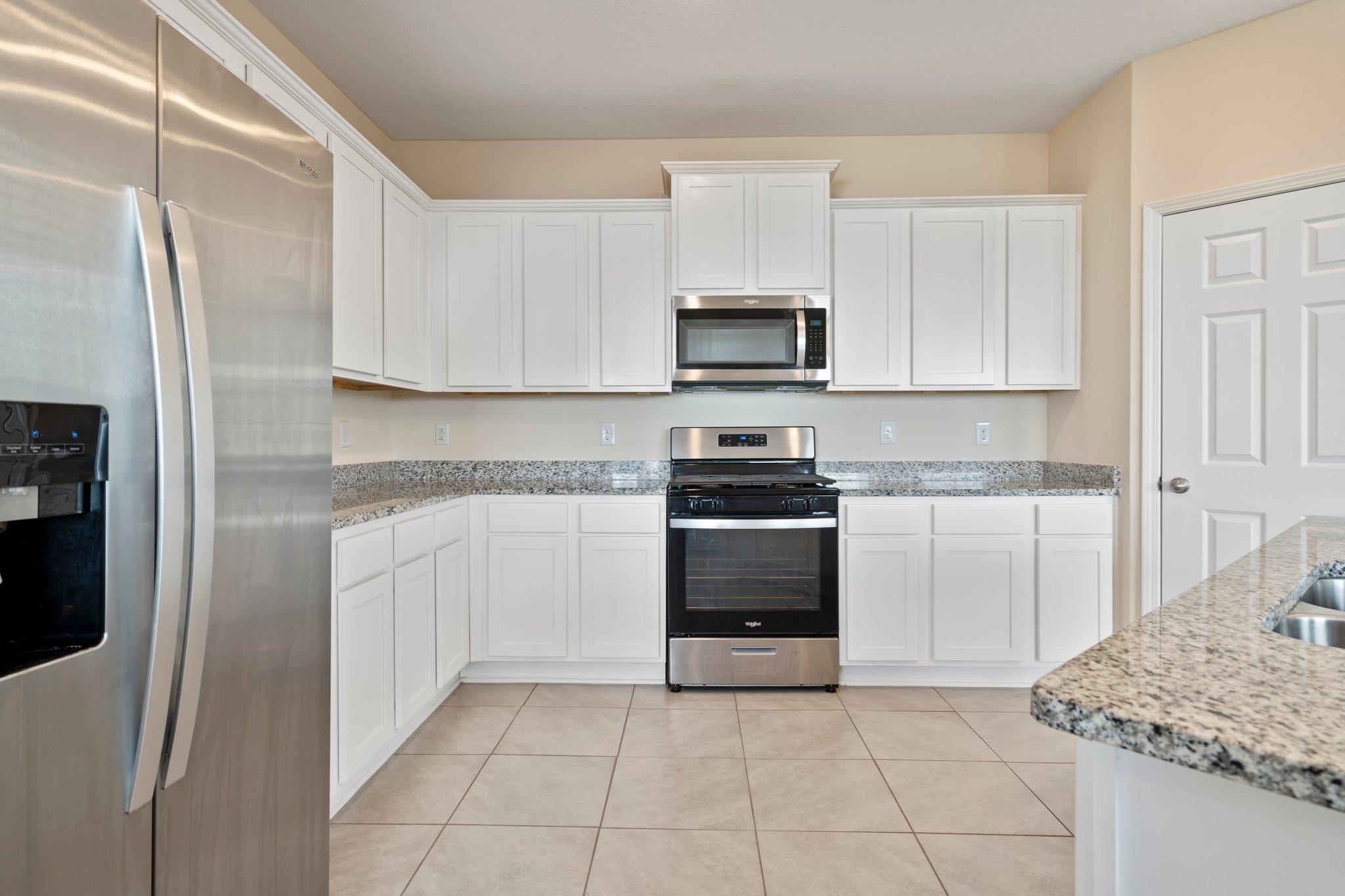 553 Coastline Way Street St. Augustine, FL 32092 - Photo 6 of 35 a kitchen with white cabinets and stainless steel appliances
