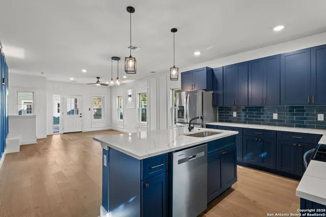 a kitchen with kitchen island granite countertop a sink cabinets and wooden floor