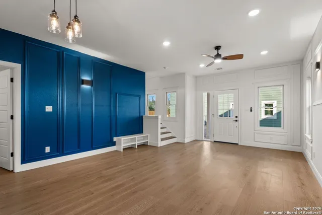 a view of an empty room with wooden floor and windows