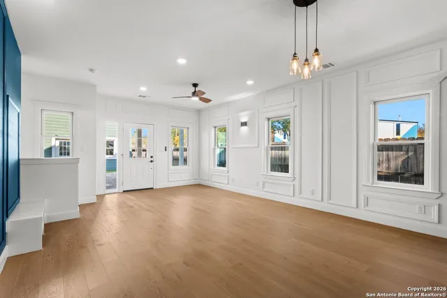 a view of an empty room with wooden floor and a kitchen