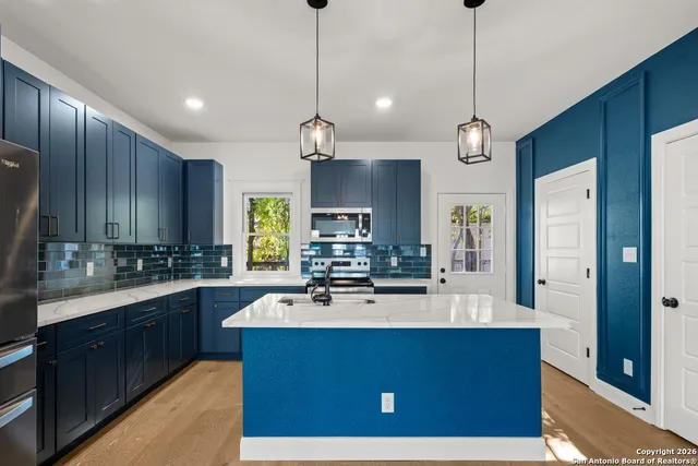 a kitchen with kitchen island granite countertop a sink refrigerator and cabinets
