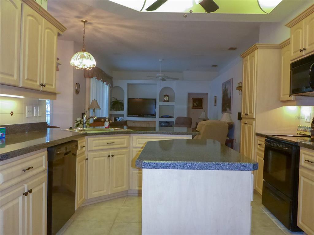 12271 Centralia Road Weeki Wachee, FL 34614 - Photo 4 of 36 a kitchen with kitchen island granite countertop a stove a sink a oven and a dining table with wooden floor
