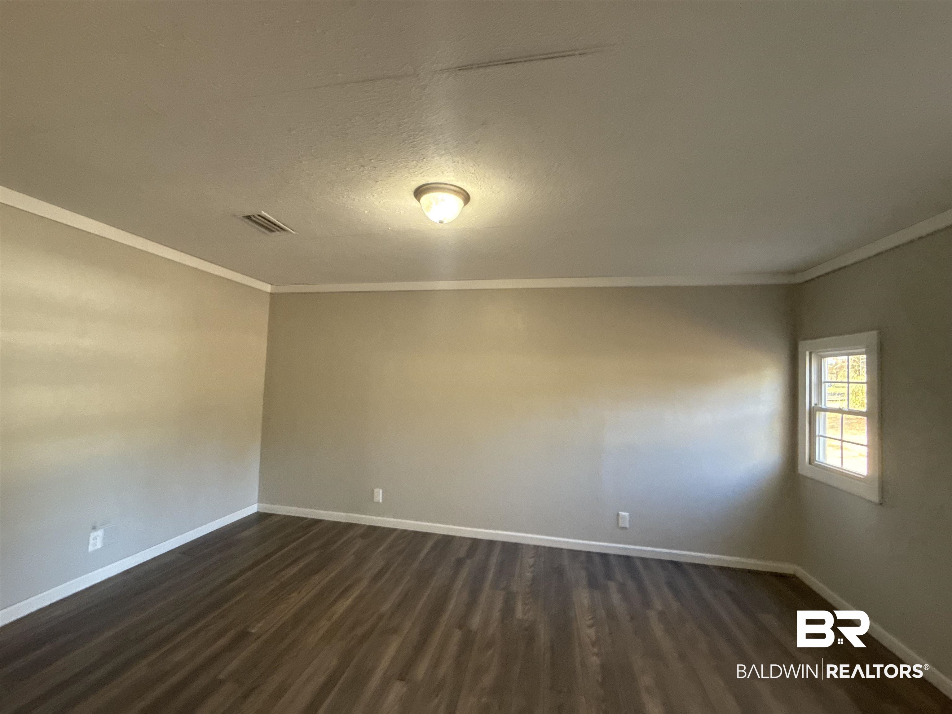 32 Slate Street Atmore, AL 36502 - Photo 5 of 16 Spare room with crown molding, dark wood-type flooring, and a textured ceiling