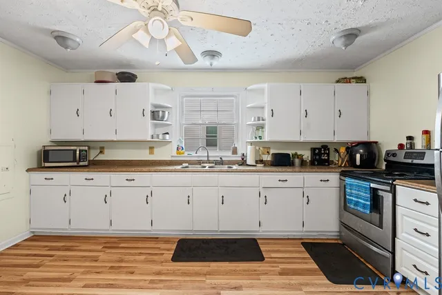 a kitchen with stainless steel appliances granite countertop a stove a sink and white cabinets