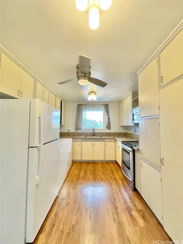a white kitchen with wooden floor and stainless steel appliances