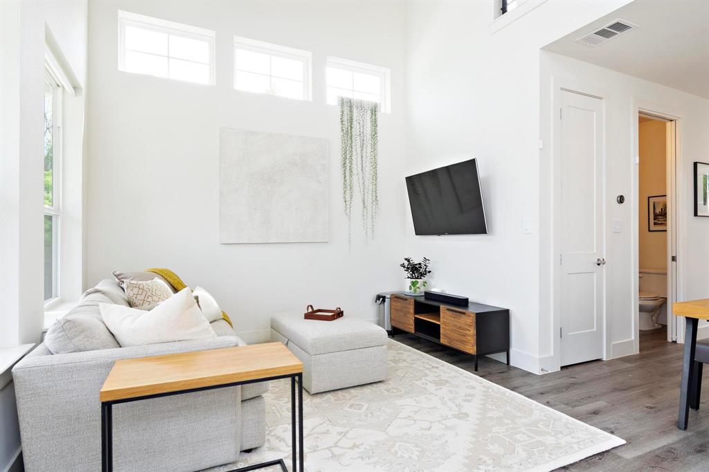 911 Stobaugh Street, Unit 2 Austin, TX 78757 - Photo 12 of 26 Living area featuring high ceilings, upper transom windows, wood-finish flooring, and a modern media console